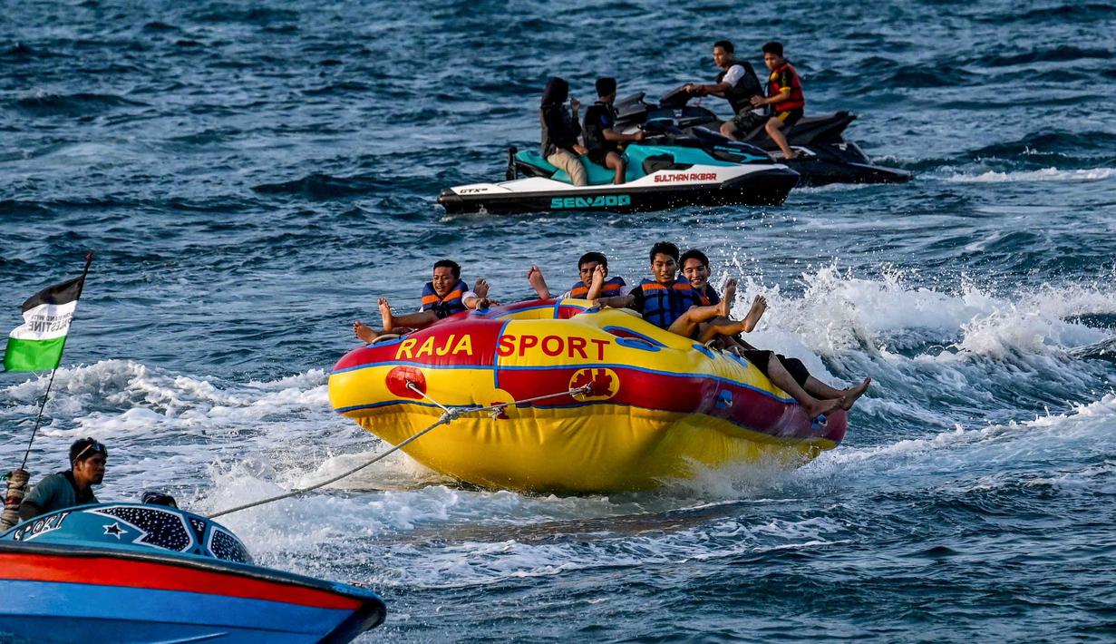 Pantai Lhoknga juga dikenal sebagai spot surfing populer. Tampak dalam foto, orang-orang saat berkumpul menikmati masa libur panjang Idulfitri di area olahraga air, Pantai Lhoknga, Aceh, pada Kamis 26 Maret 2026. (Chaideer MAHYUDDIN/AFP)