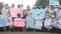 Massa dari Forum Komunikasi Nakes dan Non-Nakes Indonesia (FKHN Indonesia) membawa poster tuntutan saat menggelar aksi di kawasan Patung Kuda, Jakarta Pusat, Kamis (22/9/2022). Selain mengenakan pakaian berwarna putih, massa aksi juga terlihat membawa sejumlah atribut. (Liputan6.com/Herman Zakharia)