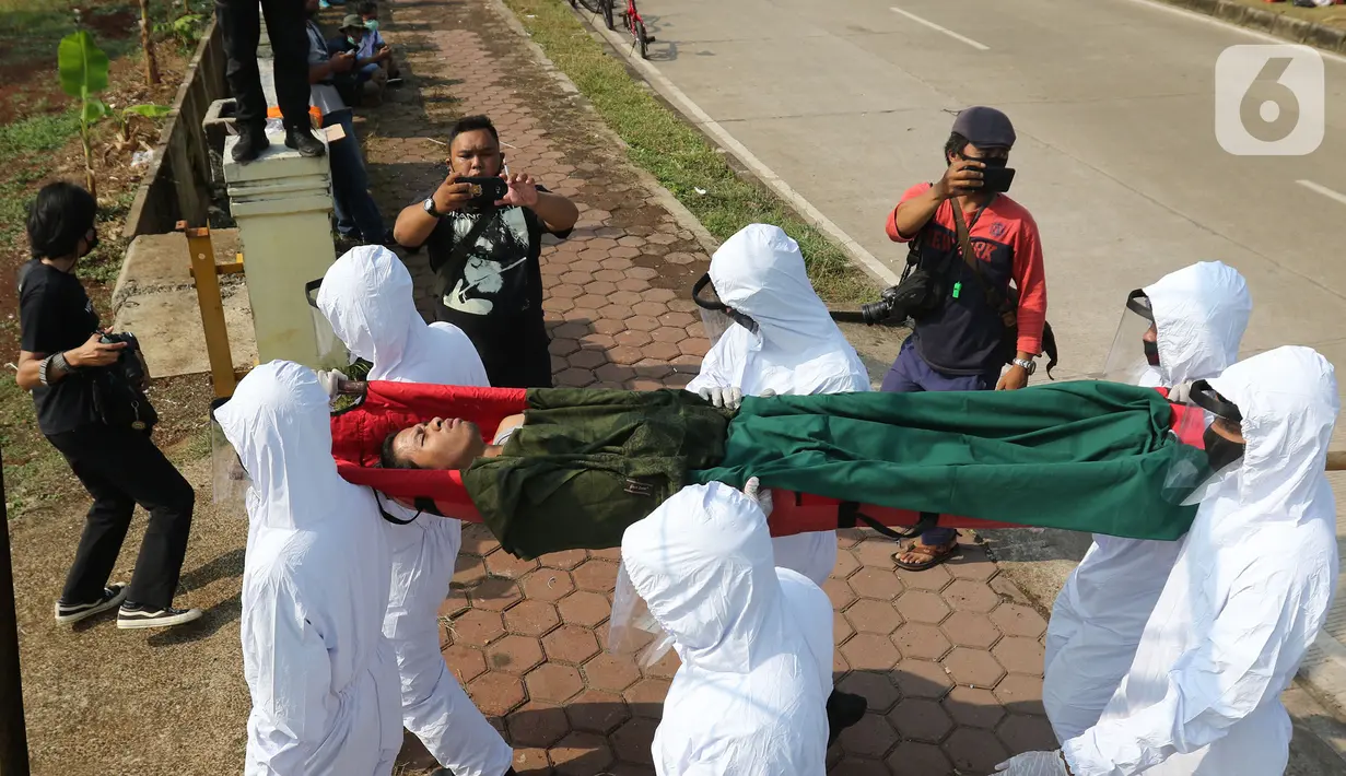 Petugas Satpol PP Kabupaten Bogor yang mengenakan pakaian hazmat menggotong warga pelanggar PSBB di kawasan Stadion Pakansari, Kabupaten Bogor, Jawa Barat, Minggu (6/9/2020). Pemkab Bogor menerapkan sanksi denda Rp 100 ribu serta sanksi sosial bagi pelanggar PSBB. (Liputan6.com/Herman Zakharia)