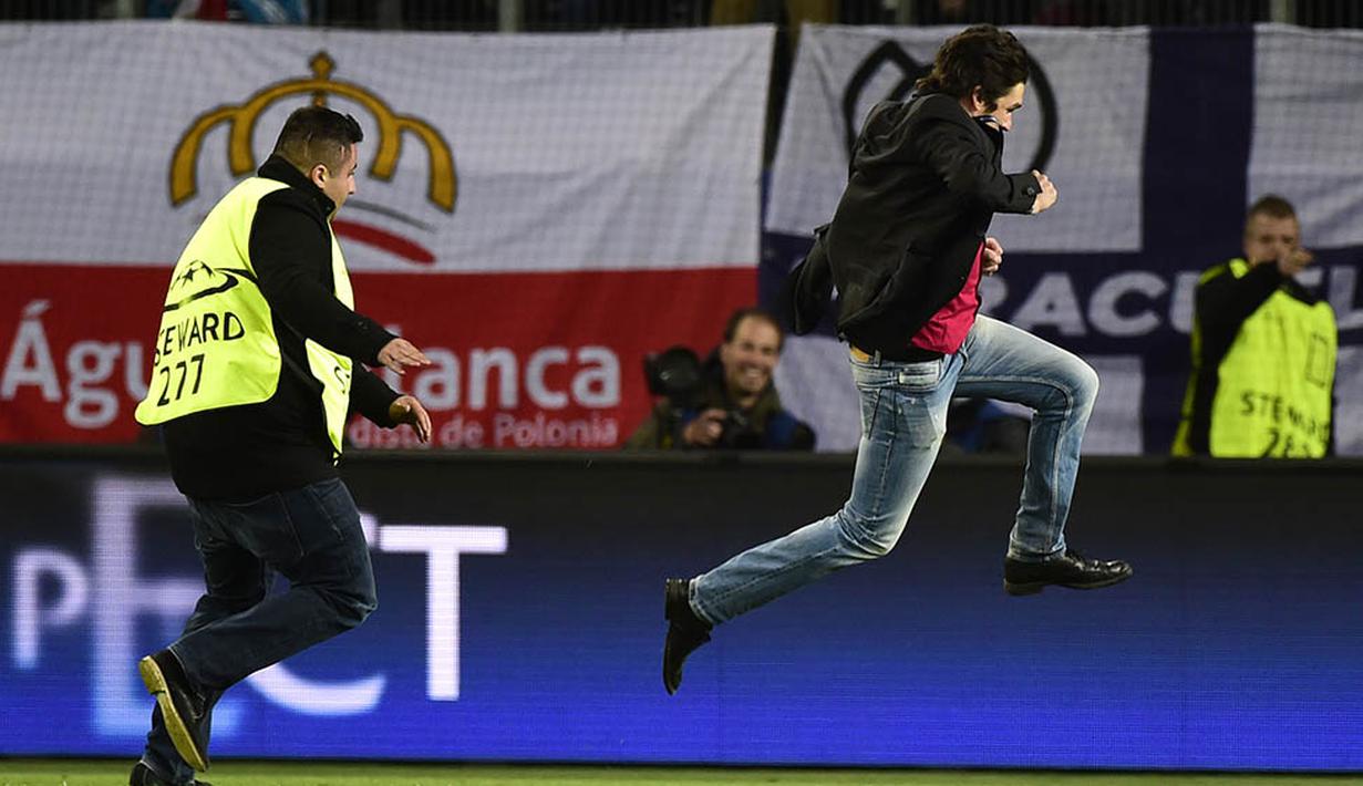 Petugas berusaha mengamankan supporter yang menerobos masuk lapangan pada laga perempat final leg pertama Liga Champions antara Wolfsburg melawan Real Madrid di Stadion Volkswagen Arena, Jerman, Rabu (6/4/2016). (AFP/John Macdougall)
