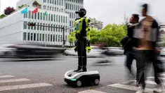 Orang-orang berjalan melewati robot polisi humanoid di Hangzhou, provinsi Zhejiang Timur, Tiongkok pada Minggu 3 Mei 2026. 15 robot humanoid dikerahkan di Hangzhou, Provinsi Zhejiang, Tiongkok. (Agatha CANTRILL/AFP)