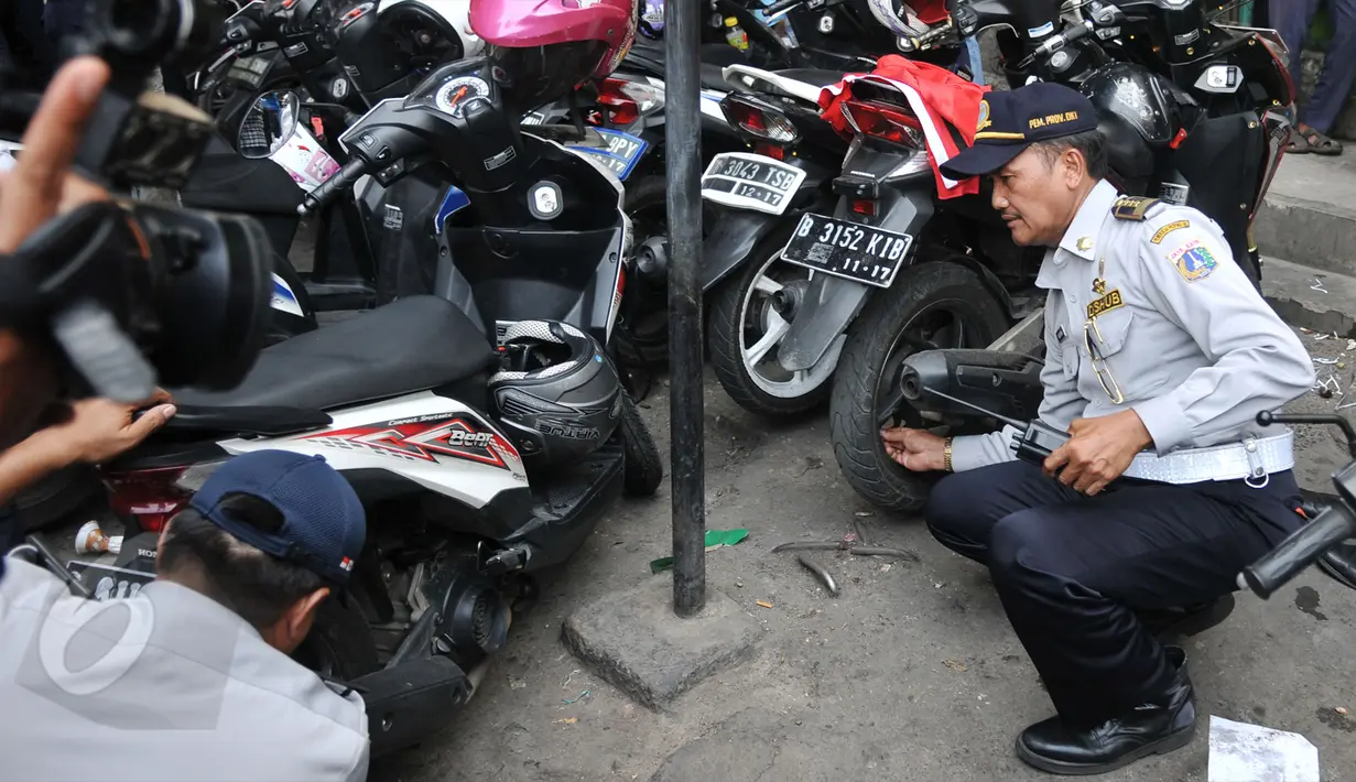 Petugas mencopot pentil motor saat melakukan razia parkir liar di kawasan Tanah Abang, Jakarta, Rabu (3/6/2015). Meski sudah disosialisasikan, kenyataannya masih banyak orang yang tak menghiraukan peraturan tersebut. (Liputan6.com/Johan Tallo)