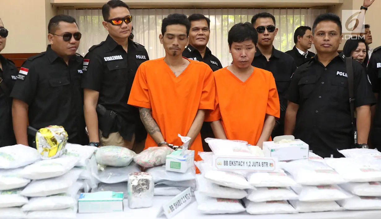 Petugas menunjukkan barang bukti beserta tersangka kasus penyelundupan ekstasi di Mabes Polri, Jakarta, Selasa (1/8). Polri dan Bea Cukai mengungkap penyelundupan 1,2 juta butir ekstasi dari Belanda senilai Rp600 miliar. (Liputan6.com/Immanuel Antonius)