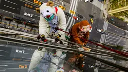 Petugas Pembersih jendela mengenakan kostum domba dan monyet saat membersihkan jendela lantai 15 sebuah hotel di Tokyo, Jepang, (21/12). Hal ini dilakukan karena prediksi dari shio domba/kambing pada 2015 ke shio monyet pada 2016. (REUTERS/Thomas Peter)