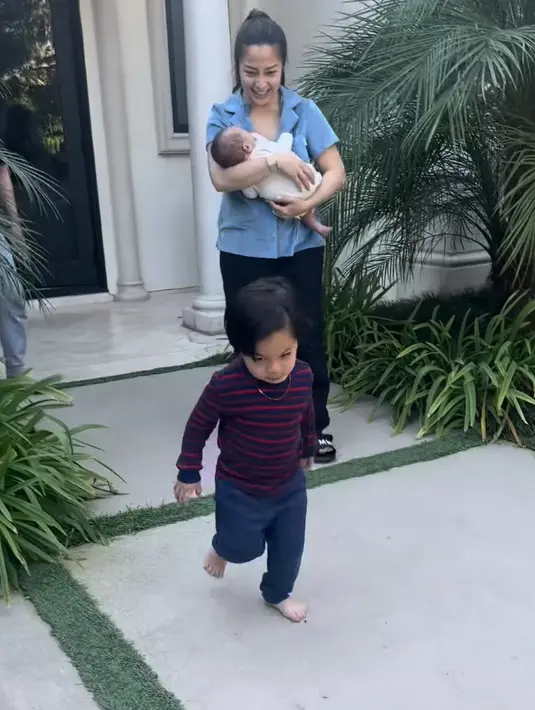 Nikita sambil menggendong putranya tampil mengenakan kemeja baby blue dipadukan celana hitam panjang. Rambutnya diikat ke belakang. [@yorafebrina]