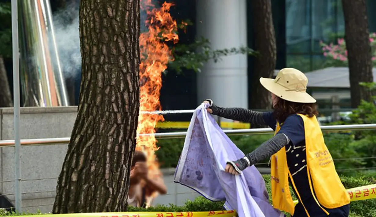 Wanita menolong Pria yang membakar dirinya sendiri depan Kantor Kedubes Jepang, Seoul, Korea Selatan, Rabu (12/8/2015). Aksi ini bentuk protes terhadap pemerintah Jepang yang selama Perang Dunia II memaksa wanita korea bekerja. (AFP PHOTO/JUNG YEON-JE)