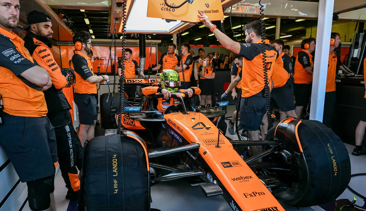 Teknisi McLaren tengah mempersiapkan mobil yang akan dipakai oleh Lando Norris dalam sesi latihan bebas Formula 1 GP Australia 2025 di Sirkuit Albert Park, Melbourne, Australia pada Jumat (14/03/2025). (AFP/Saeed Khan)