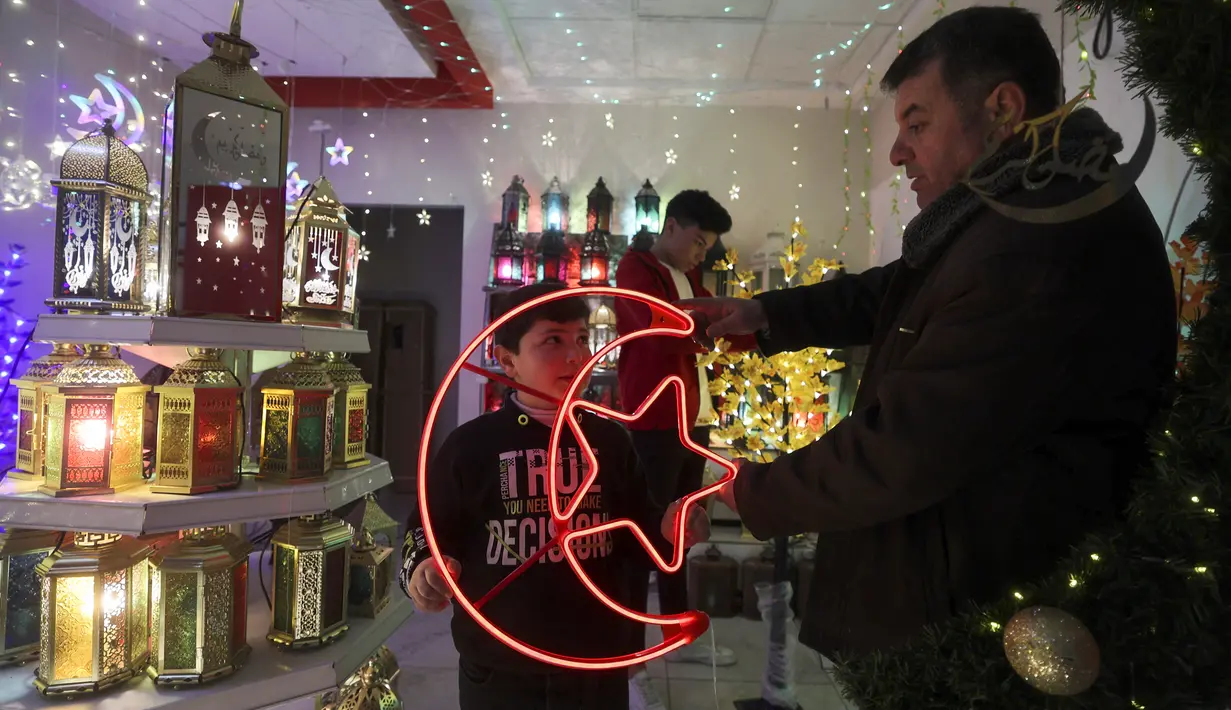 Warga Palestina berbelanja lentera tradisional "fanous" di Hebron di Tepi Barat yang diduduki pada 27 Maret 2022. Fanous merupakan lentera untuk dekorasi yang digunakan merayakan awal bulan suci Ramadan. (HAZEM BADER / AFP)