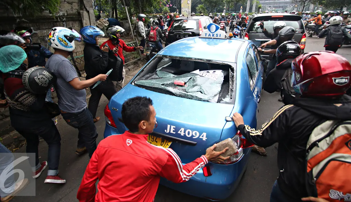 Sejumlah ojek online mengunakan batu merusak taksi di kawasan Senayan, Jakarta, Selasa (22/3). Pascabentrok ojek online melakukan sweeping dan perusakan terhadap taksi serta bajaj yang melintas di kawasan tersebut. (Liputan6.com/Immanuel Antonius)