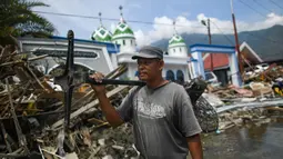 Warga membawa kipas angin yang diselamatkan dari sebuah pasar yang runtuh setelah gempa dan tsunami di  Palu, Kamis (4/10). BNPB menyebut, hingga Kamis sore, jumlah korban meninggal akibat gempa dan tsunami Palu mencapai 1.558 orang. (AFP/Jewel SAMAD)