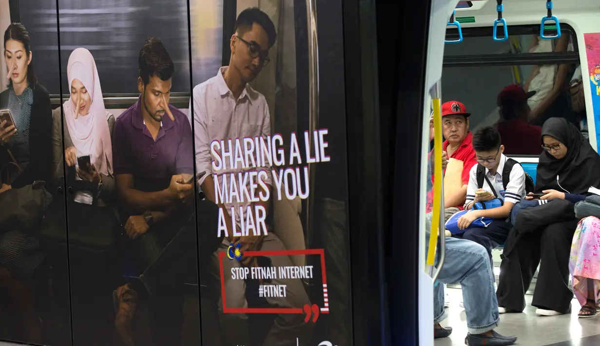 Iklan larangan penyebaran hoax atau berita bohong terpasang pada kereta di Stasiun Kereta Kuala Lumpur, Malaysia, Kamis (29/3). Penyebar hoax bakal dikenai hukuman enam tahun penjara. (AP Photo/Vincent Thian)