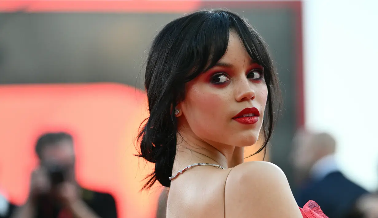 <p>Jenna mengenakan riasan wajah sempurna yang terdiri dari smokey eye berwarna ungu dan sapuan lipstik merah. (Alberto PIZZOLI / AFP)</p>