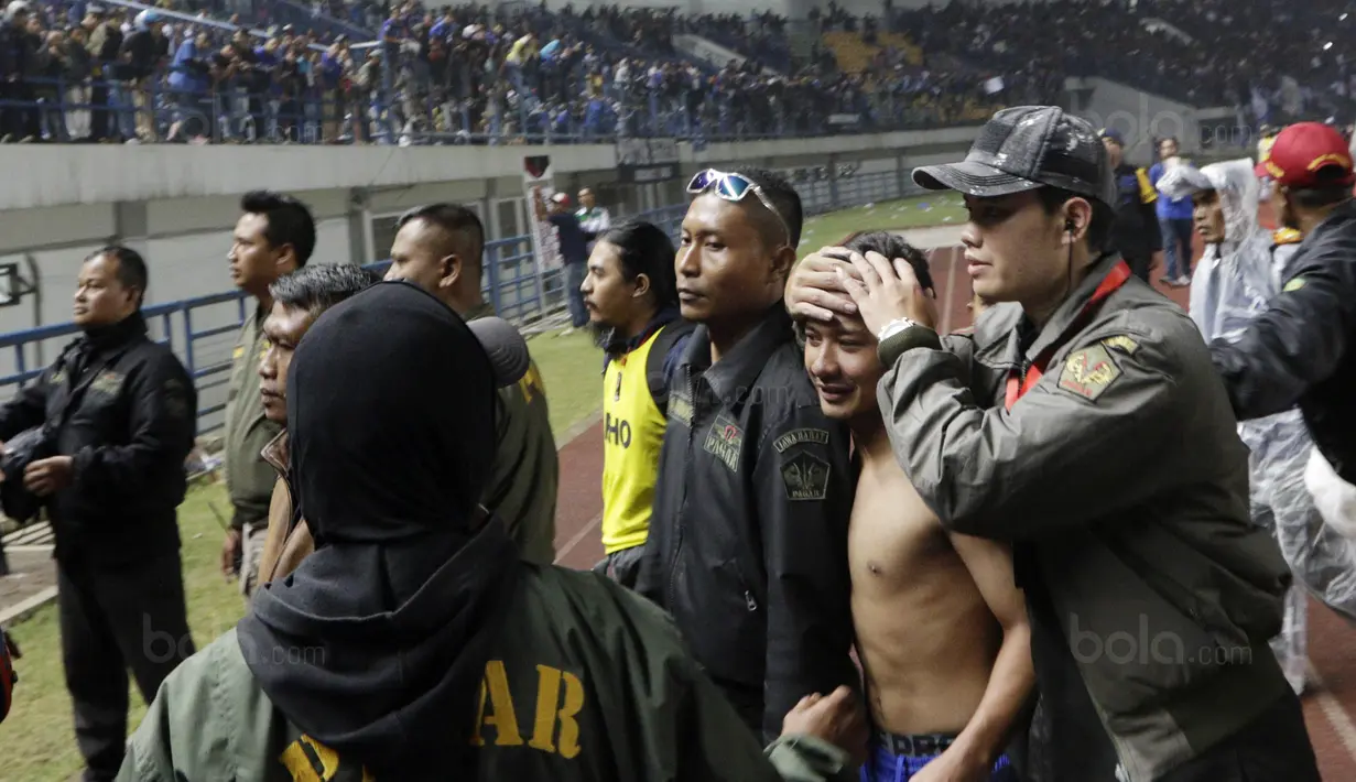 Petugas keamanan melindungi pemain Persib, Gian Zola, dari lemparan botol usai pertandingan melawan PSM pada laga Piala Presiden di Stadion GBLA, Bandung, Jumat (26/1/2018). Persib takluk 0-1 dari PSM. (Bola.com/M Iqbal Ichsan)
