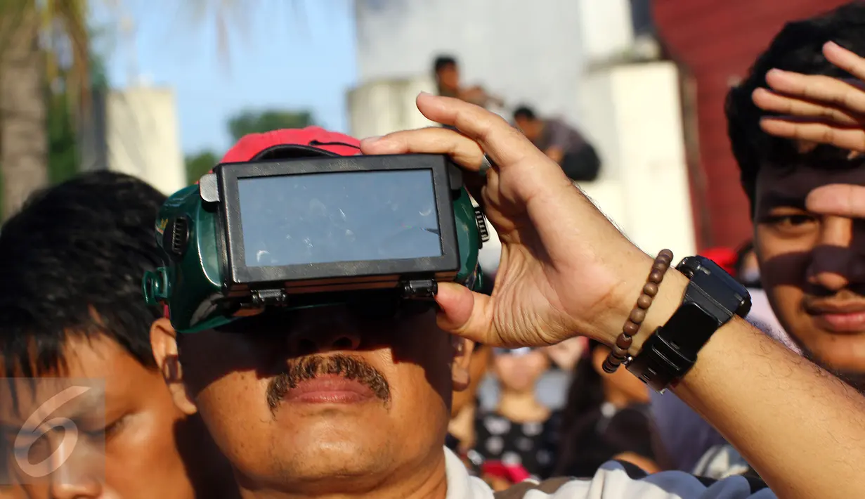 Seorang warga menggunakan sebuah alat unik untuk melihat fenomena Gerhana Matahari Total (GMT) di halaman Taman Ismail Marzuki (TIM), Jakarta, Rabu (9/3). Fenomena gerhana matahari 90% bisa diamati selama 2,11 menit. (Liputan6.com/Fery Pradolo)