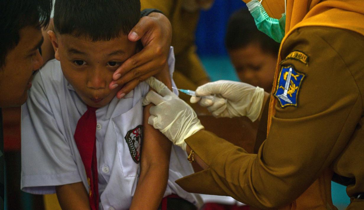 Seorang murid bereaksi saat menerima vaksin difteri di sebuah sekolah dasar di Surabaya pada Selasa 4 November 2025. Dalam pelaksanaannya, tim dari Puskesmas akan mendatangi sekolah sesuai jadwal yang telah ditentukan. Sementara, orang tua/wali murid akan menerima pemberitahuan resmi dari sekolah jauh-jauh hari sebelum imunisasi dilaksanakan. (Juni KRISWANTO/AFP)