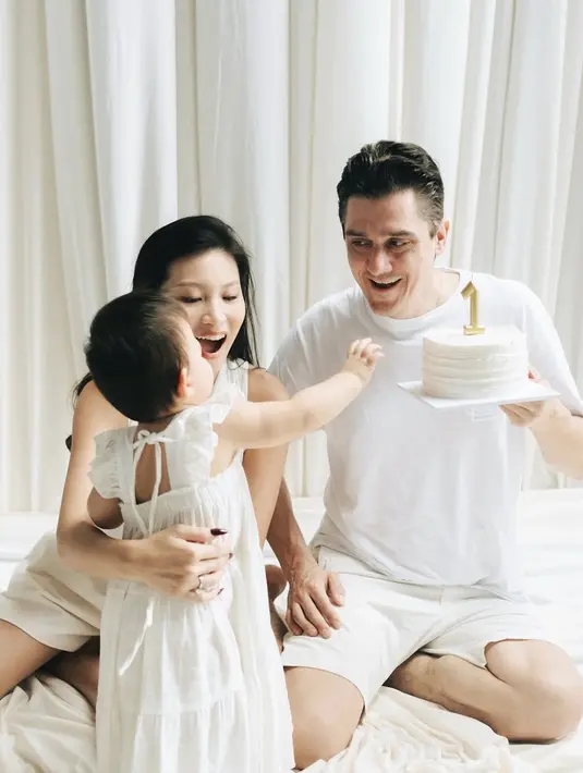 <p>Terlihat ia dan suami memberikan kue ulang tahun putih dengan lilin angka 1 warna emas. Zoe tampil menggemaskan mengenakan dress ruffle sleeveless. Dengan pita di bagian belakang. [@patriciagouw]</p>