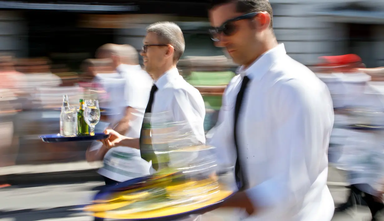Pramusaji berlari membawa nampan dalam Waiters Race ke-21 di Fetes de Geneve, Swiss, 6 Agustus 2017. Mereka beradu kecepatan sembari menjaga keseimbangan membawa nampan berisi dua gelas dan dua botol sejauh 1,8 km. (Salvatore Di Nolfi/Keystone via AP)