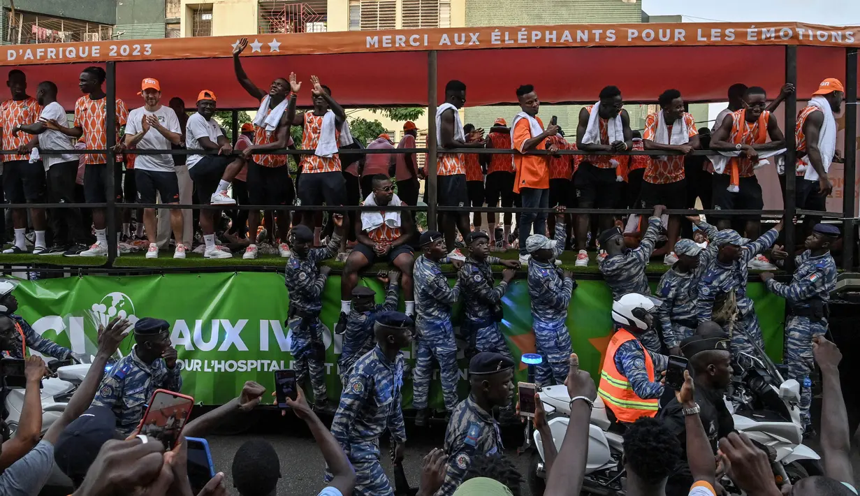Para pemain Pantai Gading melambaikan tangan kepada para pendukungnya saat mereka berparade di atas truk melalui distrik populer Treiville di Abidjan, pada 12 Februari 2024. (Issouf SANOGO/AFP)