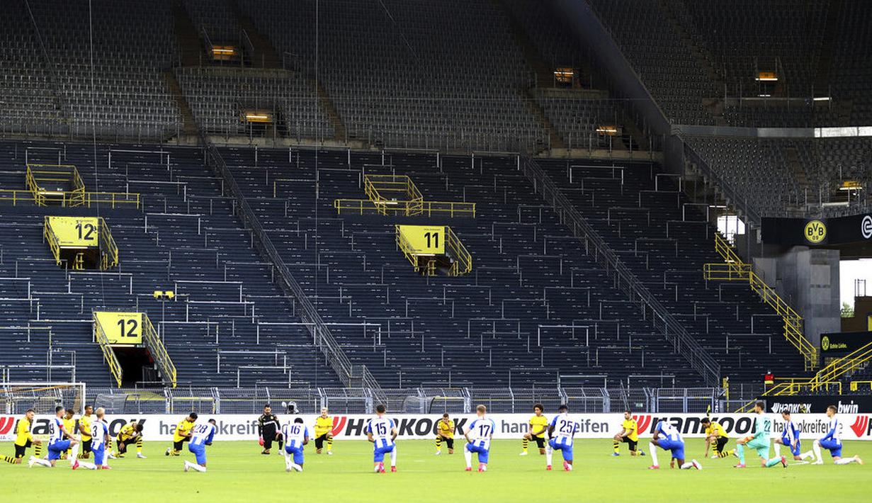 Para pemain Borussia Dortmund dan Hertha Berlin melakukan penghormatan kepada George Floyd pada laga Bundesliga di Stadion di Signal Iduna Park, Sabtu (6/6/2020). Borussia Dortmund menang 1-0 atas Hertha Berlin. (AP/Lars Baron)