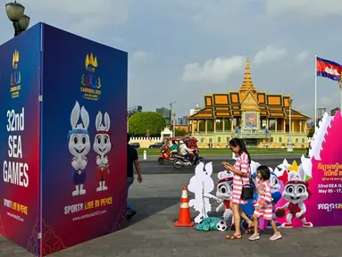 Seorang wanita dan putrinya berjalan di samping tanda menjelang upacara pembukaan Pesta Olahraga Asia Tenggara (SEA Games) ke-32 di Phnom Penh, Kamboja, Kamis (4/5/2023). (TANG CHHIN Sothy/AFP)