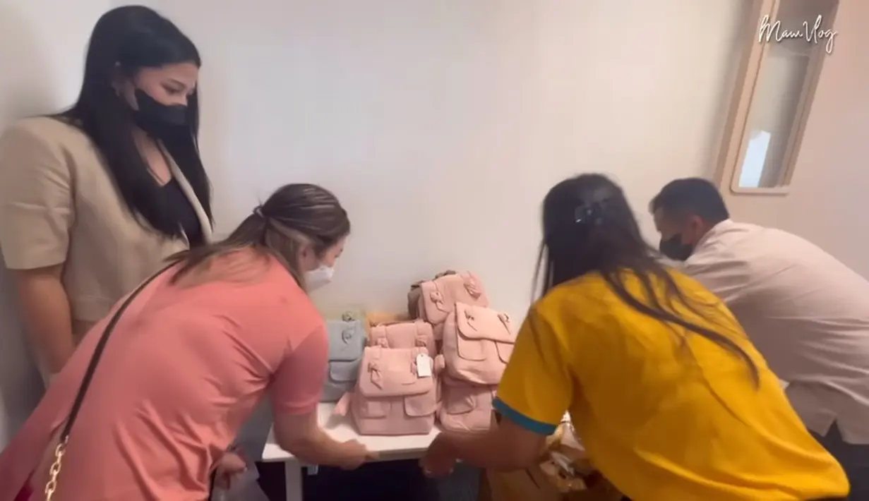 Istri mendiang Glenn Fredly dan beberapa orang tampak menyiapkan hadiah yang akan diberikan kepada teman Gewa. Tampak tas berukuran kecil dan ada tag nama diisi makanan ringan hingga minuman. [Youtube/Mutia Ayu]