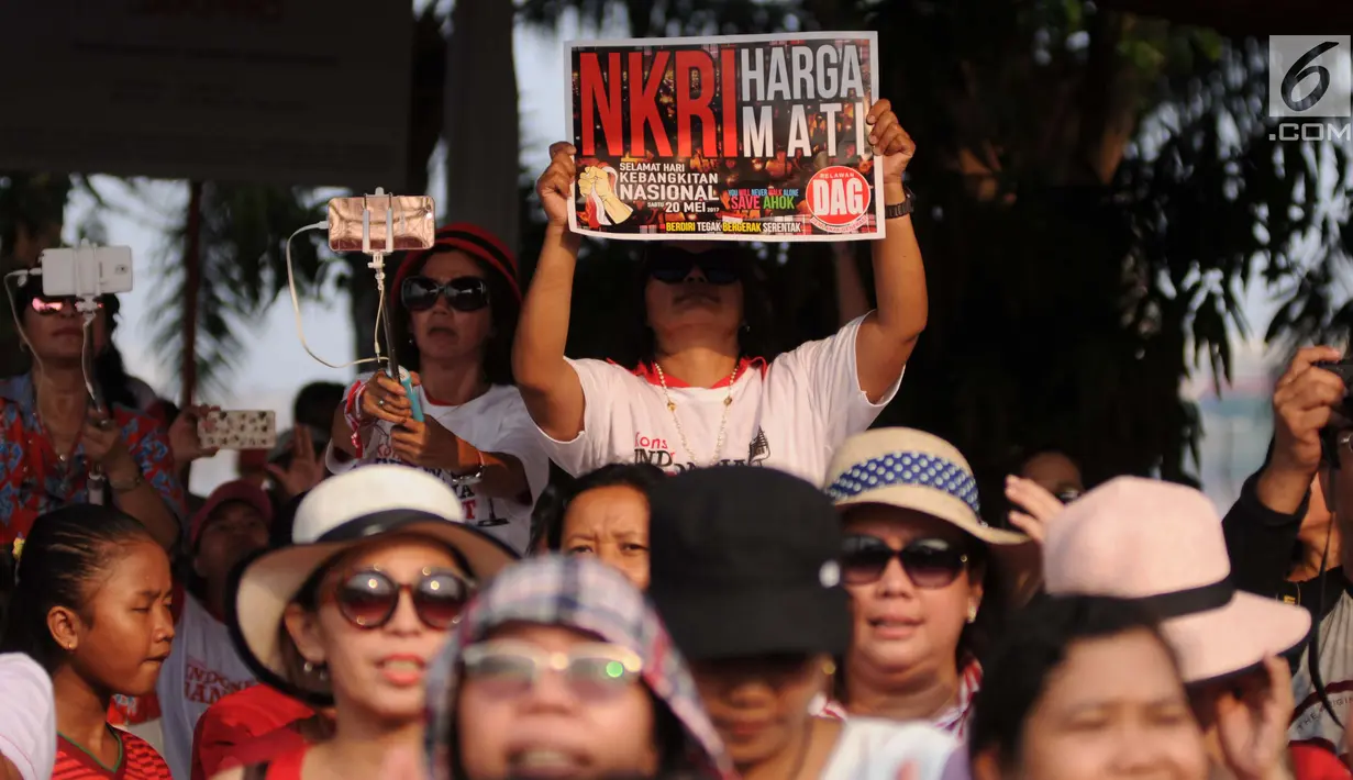 Penonton membawa poster saat hadir dalam Konser Kebangkitan Nasional di Waduk Pluit, Penjaringan, Jakarta Utara, Sabtu (20/5). (Liputan6.com/Gempur M. Surya)