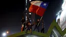 Sejumlah Suporter berada diatas atap mengibarkan bendera nasional Chile merayakan kemenangan Chile atas Uruguay di Copa America 2015 di Santiago, Chile, (25/6/2015). Chile melaju ke semifinal usai mengalahkan Uruguay 1-0. (REUTERS/Pablo Sanhueza)