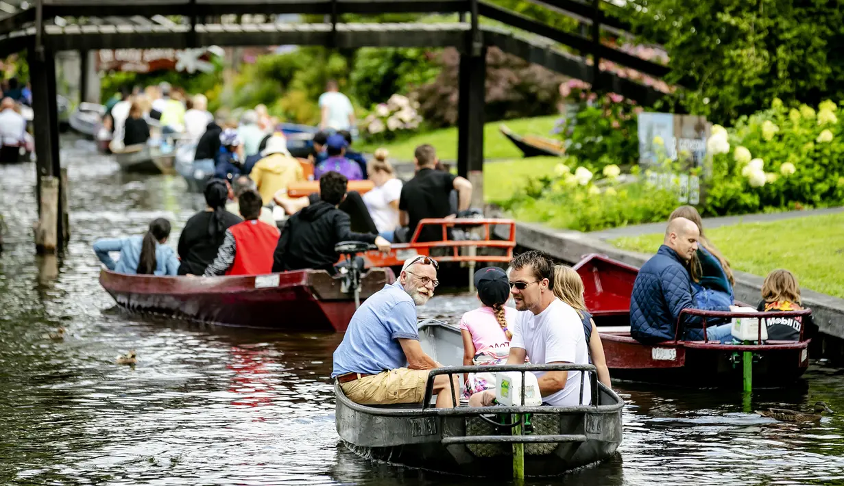 Wisatawan menaiki perahu menyusuri sungai di Giethoorn yang menjadi tujuan wisata favorit di Belanda pada 6 Agustus 2019. Mendapat julukan 'Venice of the North', kota tersebut menggunakan kanal-kanal sebagai jalan dan lalu lalang transportasi sehari-hari. (Robin van Lonkhuijsen/ANP/AFP)