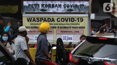 Warga melihat tanda peringatan bahaya COVID-19 di sekitar Pasar Blok A Tanah Abang, Jakarta, Selasa (1/9/2020). Guna meningkatkan kewaspadaan masyarakat, muspida kecamatan Tanah Abang memajang peti mati dilengkapi data jumlah korban COVID-19 di wilayah tersebut. (Liputan6.comHelmi Fithriansyah)