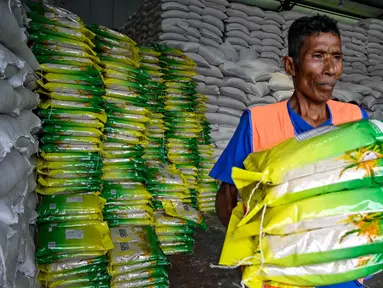 Seorang pekerja membawa karung-karung beras di gudang Badan Urusan Logistik (Bulog) di Lambaro, Provinsi Aceh pada 29 Desember 2025. Badan Urusan Logistik (Bulog) memastikan ketersediaan beras di Pulau Sumatera dalam kondisi aman dan mencukupi, khususnya untuk memenuhi kebutuhan masyarakat yang terdampak bencana banjir dan longsor di sejumlah wilayah. (CHAIDEER MAHYUDDIN/AFP)