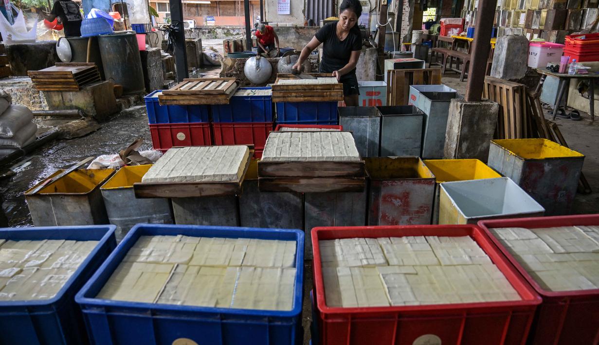 Seorang pekerja memotong tahu di sebuah pabrik, Surabaya, Jawa Timur pada Kamis 5 Februari 2026. (JUNI KRISWANTO/AFP)