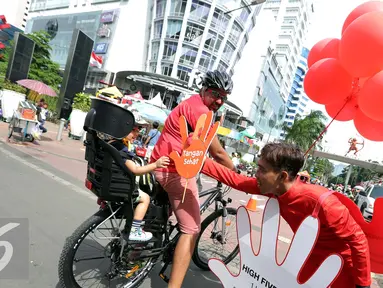 Seorang lelaki memberikan cinderamata pada bocah saat acara Car Free Day, Jakarta, Minggu (2/10) Dalam rangka menyambut Hari Cuci Tangan Sedunia, Lifebouy memberikan pengetahuan mengenai pentingnya cuci tangan. (Liputan6.com/Helmi Afandi)