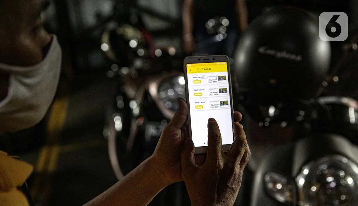 Pekerja mengakses aplikasi saat akan menurunkan sepeda motor di Soul Parking, Kebon Kacang, Jakarta, Jumat (21/1/2022). Tempat parkir vertikal tersebut bisa menyimpan lebih banyak motor di atas lahan sempit. (Liputan6.com/Faizal Fanani)