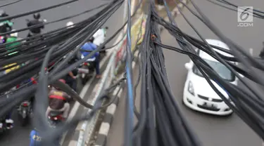 Instalasi kabel semrawut menjuntai di Jalan Dewi Sartika, Jakarta Timur, Sabtu (19/1). Selain mengganggu keindahan kota, kondisi tersebut juga berbahaya karena dapat memicu hubungan pendek arus listrik. (Liputan6.com/Immanuel Antonius)