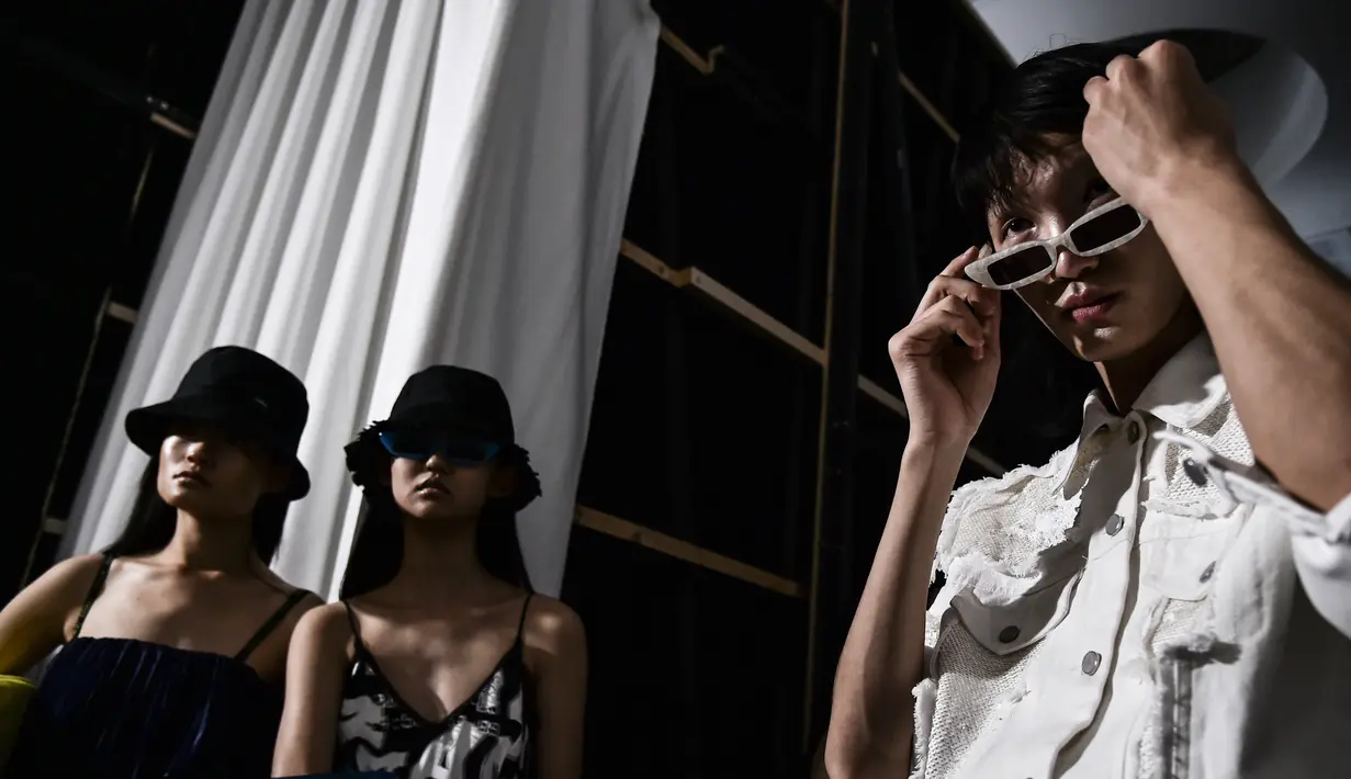 Tiga model berpose di belakang panggung sebelum berjalan di atas catwalk mengenakan busana Women Spring/Summer 2019 karya Annakiki selama Milan Fashion Week di Italia (19/9). (AFP Photo/Marco Bertorello)