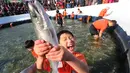 Seorang anak bergembira saat mendapatkan ikan selama lomba memancing ikan trout di sungai yang membeku di Hwacheon, Korea Selatan (6/1). (AP Photo/Ahn Young-joon)