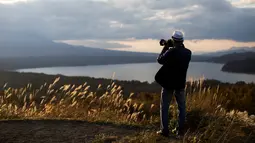 Turis mengambil foto Gunung Fuji di samping danau Yamanaka di desa Yamanakako, Prefektur Yamanashi, Jepang (1/11). Gunung Fuji dikelilingi oleh tiga kota yaitu Gotemba (timur), Fuji-Yoshida (utara) dan Fujinomiya (barat daya). (AFP Photo/Behrouz Mehri)