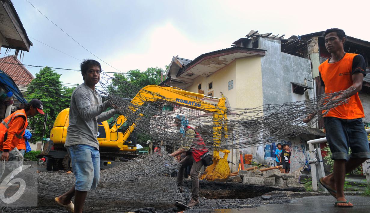 Petugas mengangkat besi Jembatan Inspeksi Kali Grogol yang ambles di Komplek Hankam, Slipi, Jakarta, Senin (21/3). Dinas Pemprov DKI sedang melakukan perbaikan di kawasan depan Komplek HANKAM slipi Jakarta Barat. (Liputan6.com/Faisal R Syam)