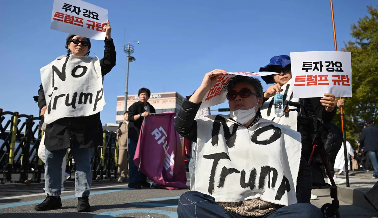Para demonstran Korea Selatan yang mengenakan spanduk bertuliskan "Tolak Trump" memegang plakat selama demonstrasi yang mengecam tekanan Presiden AS Donald Trump untuk meningkatkan investasi Korea Selatan di AS, di Gyeongju pada 29 Oktober 2025, menjelang KTT Kerja Sama Ekonomi Asia-Pasifik (APEC). (Jung Yeon-je/AFP)