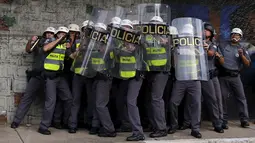 Polisi Anti Huru hara melindungi diri di balik perisai saat diserang para demonstran, Brasil, Jumat (8/1/2016). Pengunjuk rasa protes terhadap kenaikan tarif untuk bus kota di Sao Paulo. (Reuters/Nacho Doce)