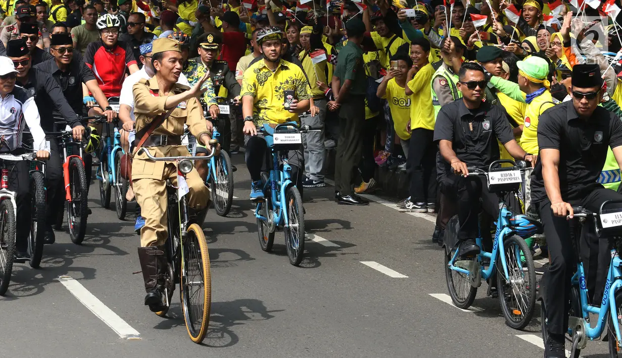 Presiden Joko Widodo atau Jokowi menyapa warga saat mengikuti Bandung Lautan Sepeda, Sabtu (10/11). Jokowi bersepeda mengelilingi Kota Bandung. (Liputan6.com/Angga Yuniar)