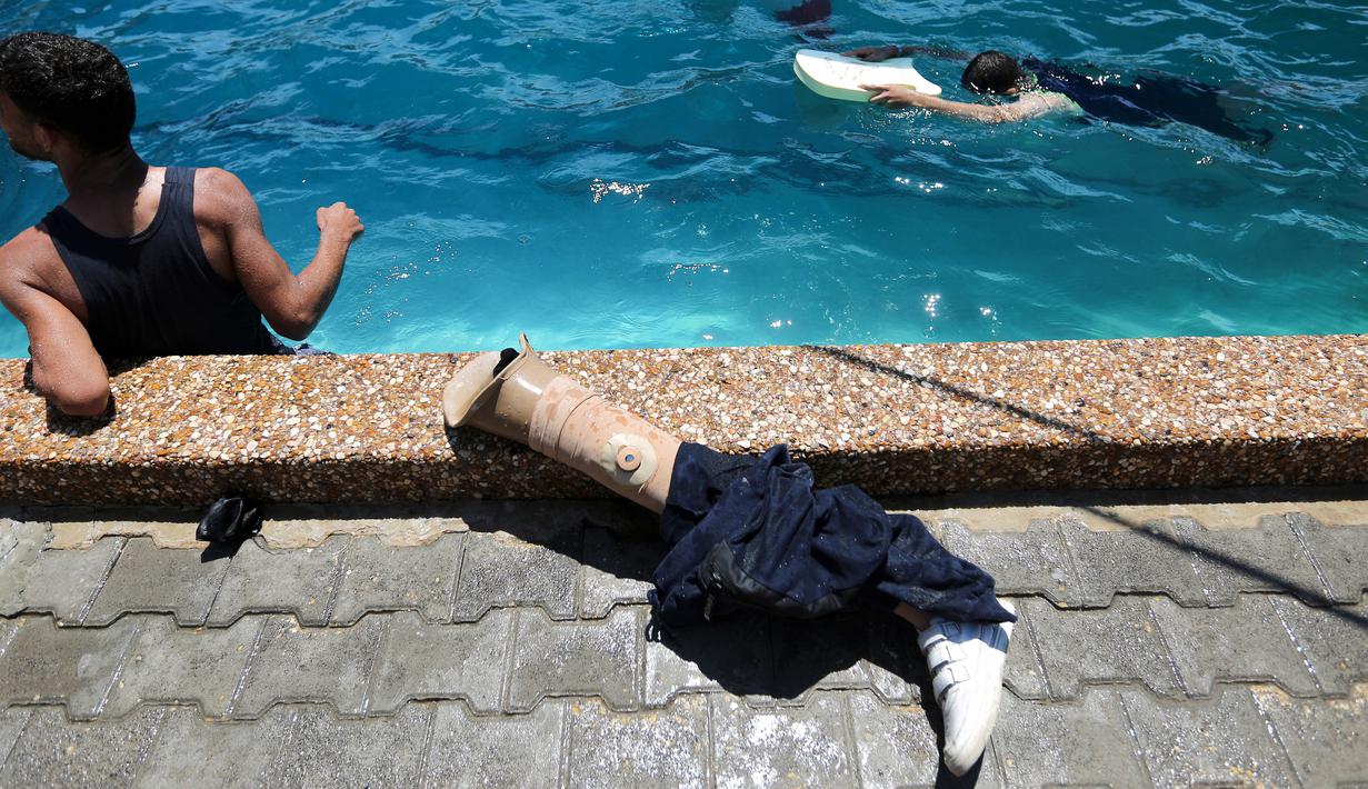 Kaki palsu terlihat di dekat kolam renang ketika warga Palestina berlatih di bawah instruksi Majdi al-Tatar di Gaza (30/7/2019). Tatar, yang kehilangan kaki kanannya akibat kecelakaan pada masa kecilnya, melatih warga Palestina yang diamputasi selama konflik dengan Israel. (AFP Photo/Mahmud Hams)
