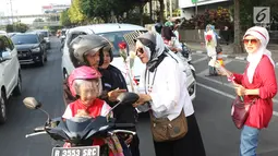 Relawan Jokowi saat membagikan bunga mawar kepada pengendara motor di Kawasan Sarinah, Jakarta, Minggu (29/9/2019). Aksi bagi bunga tersebut merupakan aksi damai kami bersama Jokowi. (Liputan6.com/Angga Yuniar)