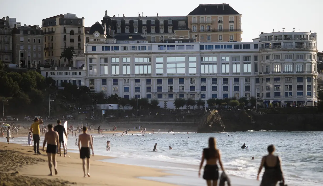 Orang-orang berjalan di pantai di depan tempat pertemuan G7 Le Bellevue di Biarritz, Prancis barat daya 21/8/2019).  Para pemimpin negara-negara G7 akan bertemu Sabtu selama tiga hari di kota resor Biarritz di barat daya Prancis. (AFP Photo/Iroz Gaizka)
