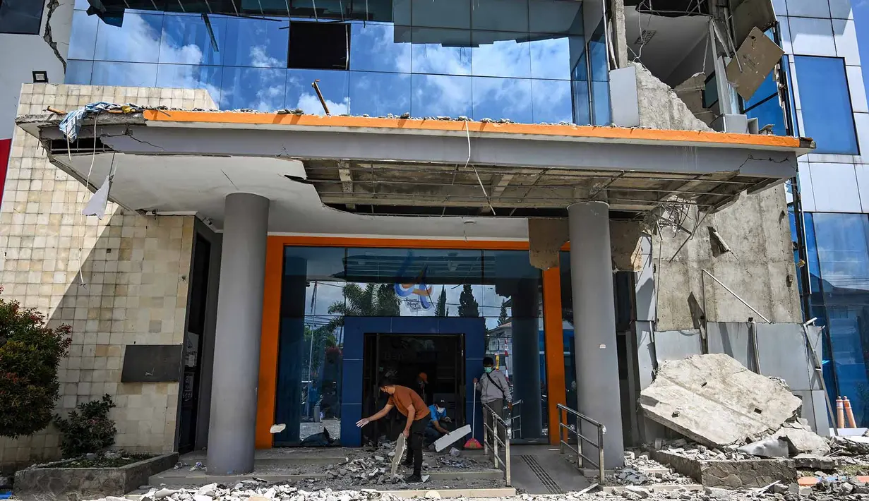Pekerja membersihkan puing-puing dari sebuah gedung bank yang rusak akibat gempa berkekuatan magnitudo 7,7 di Ruteng, Manggarai, Nusa Tenggara Timur, Minggu, 16 Agustus 2026. (AFP/ Juni Kriswanto)