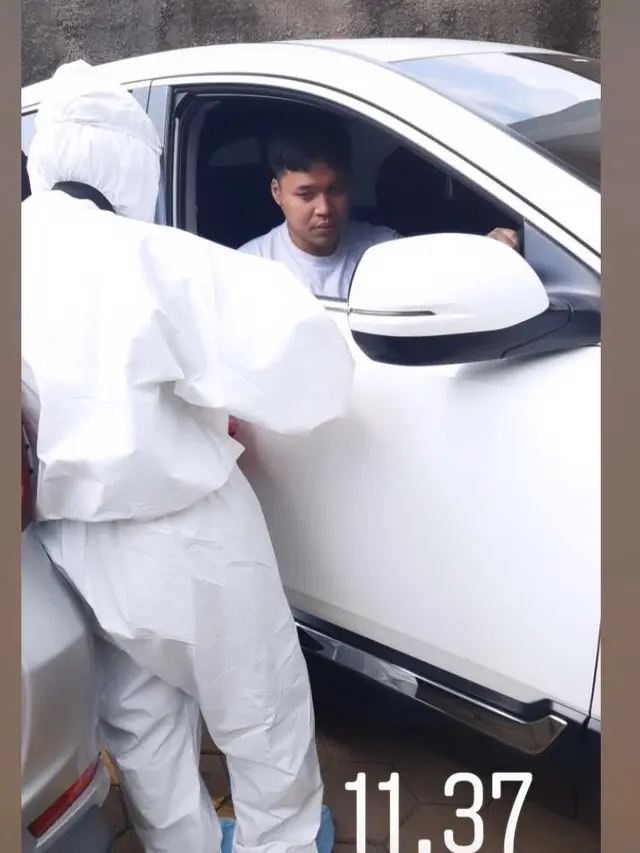 Rivelino Wardhana diketahui sedang berurusan dengan petugas medis yang mengenakan pakaian Alat Pelindung Diri (APD) lengkap.