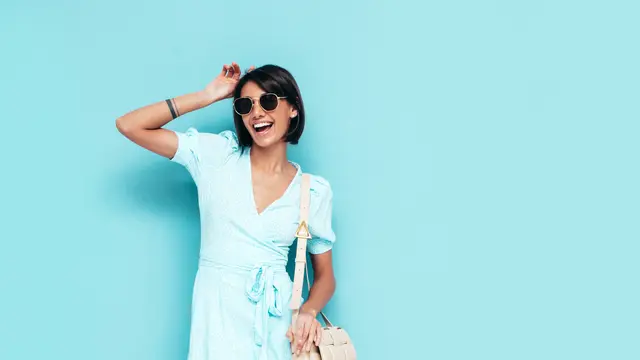 Seorang perempuan dengan dress biru dan kacamata hitam sedang berpose (Foto Dok: Freepik/halayalex)
