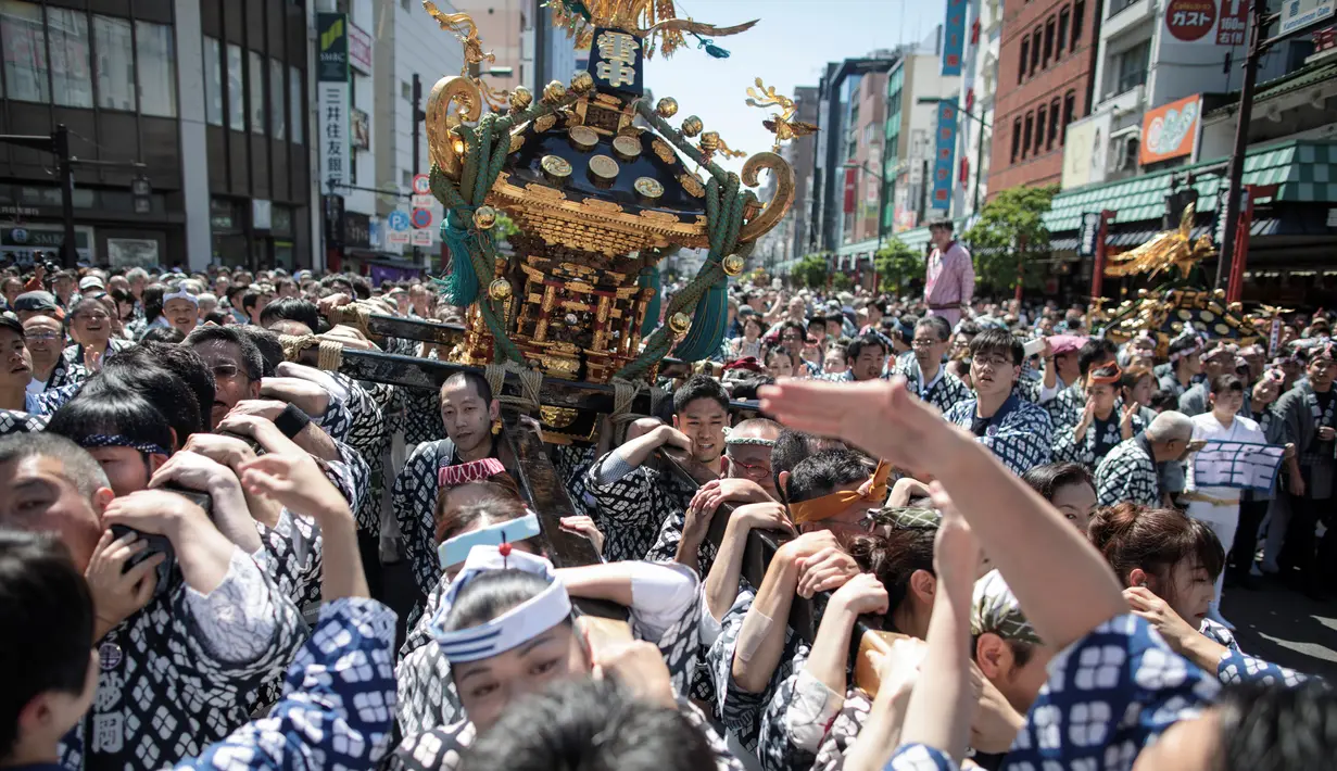 Para peserta membawa kuil portabel atau "Mikoshi" pada Festival Sanja Matsuri di luar kuil Sensoji, Tokyo, Minggu (20/5). Sanja Matsuri adalah festival tahunan di distrik Asakusa yang diadakan pada akhir pekan ketiga pada bulan Mei. (AFP/Behrouz MEHRI)