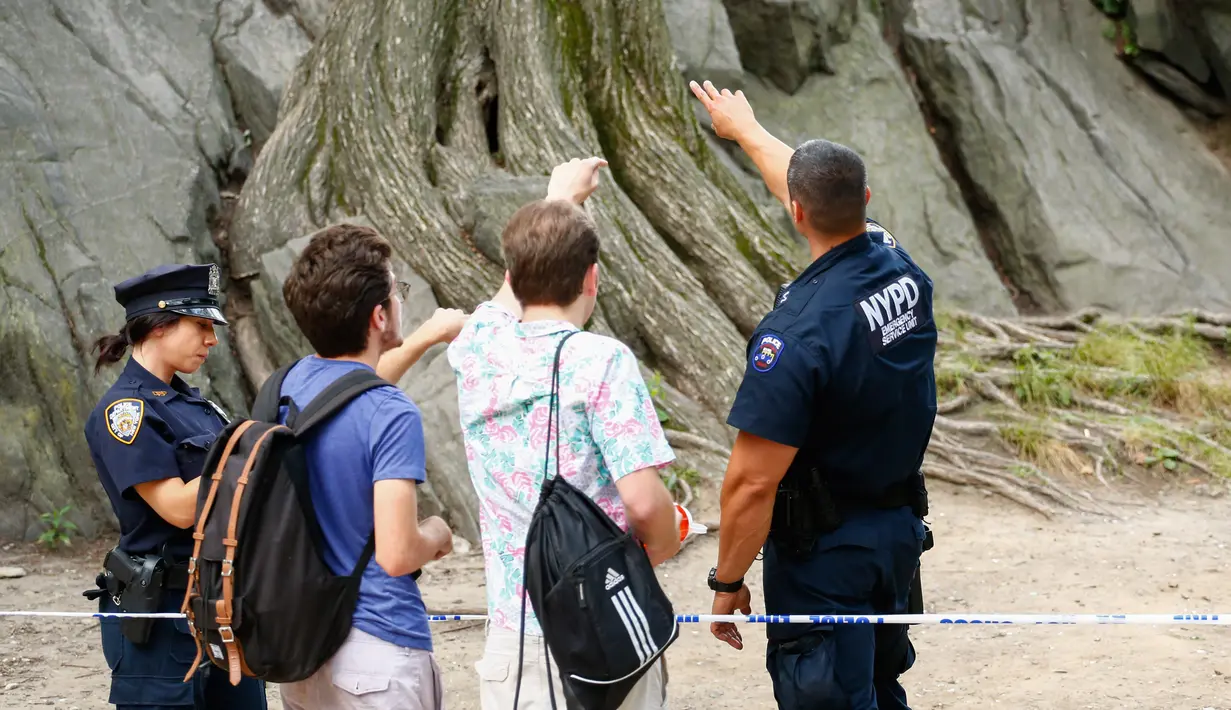 Saksi mata memberi kesaksian kepada petugas kepolisian setelah ledakan di Central Park, New York, Minggu (3/7). Seorang pemuda menjadi korban ledakan tersebut yang menyebabkan kakinya hampir putus. (Kena Betancur/AFP)