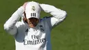 Pelatih Real Madrid Zinedine Zidane merapikan topinya saat menghadiri sesi pelatihan di fasilitas pelatihan Valdebebas di Madrid (15/3). Zidane kembali melatih Real Madrid menggantikan Santiago Solari. (AFP Photo/Gabriel Bouys)